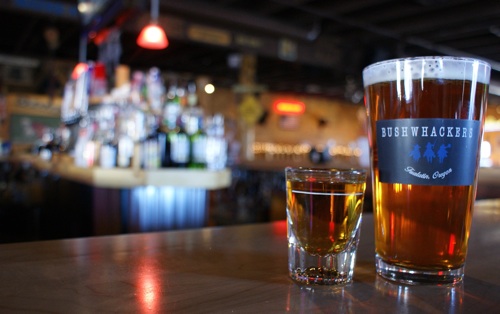 A Bushwhackers pint of beer and a shot of whiskey side by side on the bar in the afternoon