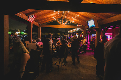 Guests gathered in the evening on the covered outdoor patio under string lights