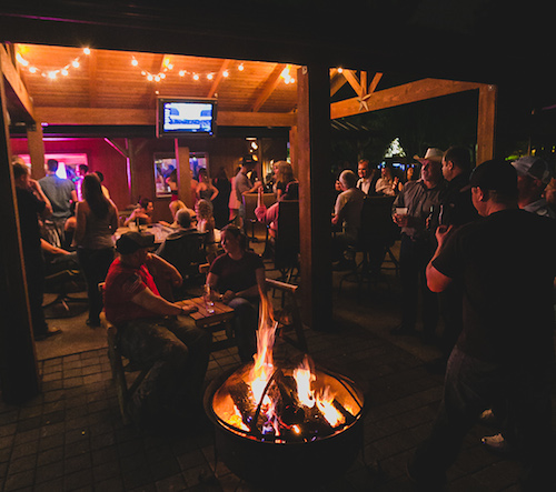 Friends talking around the blazing fire pit on the covered patio at night